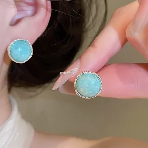 Detail view of a retro silver-toned stud earring with a round turquoise agate stone.