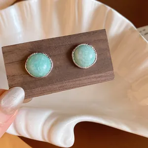 Close-up of vintage light green agate stone stud earrings with silver textured bezel