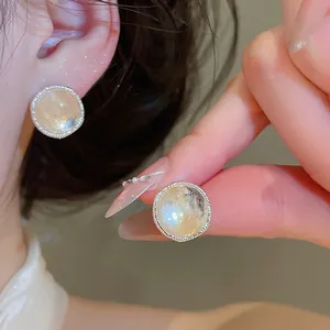 Close-up view of vintage-style agate stone stud earrings with a textured silver-toned border