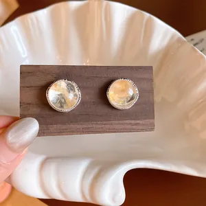 Elegant round agate stone stud earrings with silver textured border on display