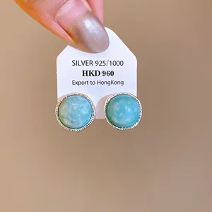 Close-up view of vintage silver stud earrings featuring round blue agate stones and textured rims