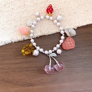 Dettaglio di un braccialetto di perle con ciondoli di frutta in resina per le vacanze.