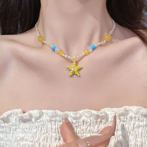 Dettaglio di una collana di perle in resina colorata con un ciondolo a stella gialla.