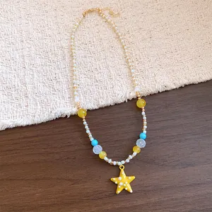 Dettaglio collana di perline con ciondolo a stella marina gialla e resina colorata