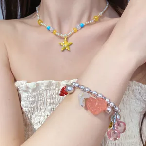 Dettaglio della collana di perle con stella marina e bracciale con ciondoli di frutta.