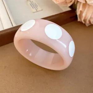 Detail view of a pink resin bangle featuring a stylish white polka dot pattern.