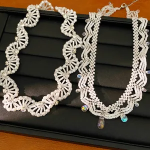 Detailed macro view of intricate white beaded lace necklace with crystal teardrops