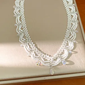Macro detail of white glass beaded lace necklace with iridescent teardrop crystals.