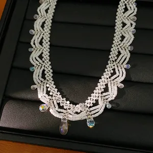 Close-up view of a white beaded lace necklace with iridescent crystal drop pendants