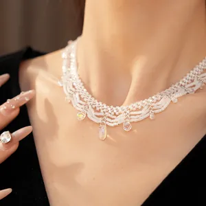 Close-up of an elegant white beaded lace necklace featuring iridescent glass teardrop charms