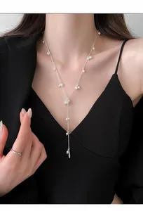 Detailed view of elegant French style Y-shaped pearl necklace worn with black blazer.