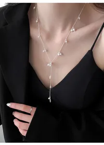 Elegant silver Y-shaped necklace with small pearls worn by a model in a black suit.