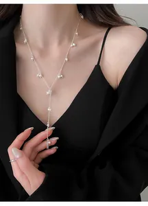 Close-up of elegant French style pearl Y-necklace on a model wearing black dress.