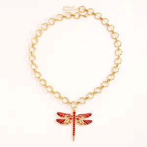 Dettaglio della collana libellula dorata con strass rossi e ali in smalto decorato.