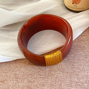 Gros plan détaillé sur un bracelet large en résine avec motif marbré rouge et fil doré