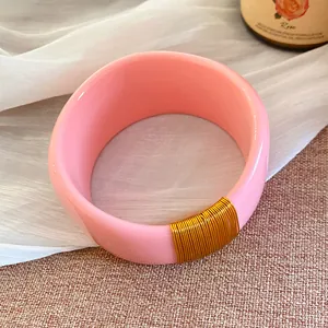 Vue détaillée d'un large bracelet en résine rose avec enroulement de fil doré chic