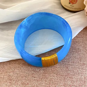 Vue détaillée d'un bracelet large en résine bleue marbrée avec fil doré torsadé