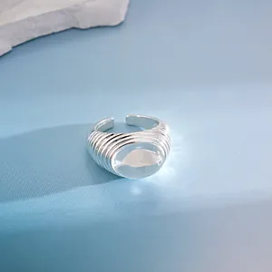 Primo piano di anello aperto argento con trama a pieghe e grande cabochon trasparente
