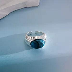 Dettaglio di un anello regolabile vintage con texture a pieghe e pietra blu