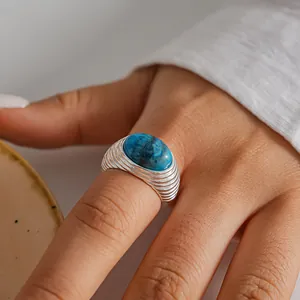 Primo piano di un anello vintage in argento con una grande pietra blu ovale sul dito
