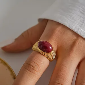 Primo piano di un anello a pieghe in oro vintage con pietra cabochon rosso scuro