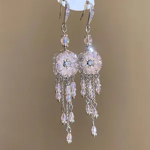 Gros plan sur des boucles d'oreilles vintage fleurs roses avec de longs pompons perlés
