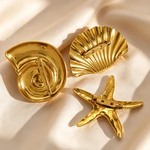 Detail view of gold marine brooches set featuring starfish, shell and conch designs.