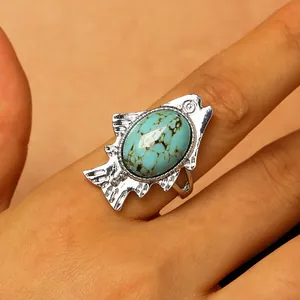 Detailed view of a vintage silver-finish fish ring with an oval turquoise stone