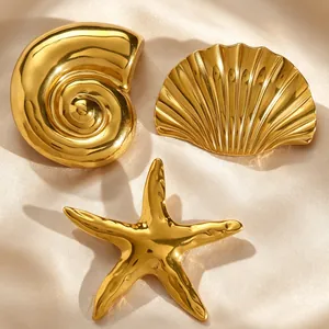 Detailed macro view of vintage gold seashell starfish and conch brooches on satin cloth