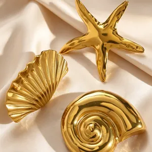 Close-up of polished gold sea snail, starfish, and shell brooches on silk fabric
