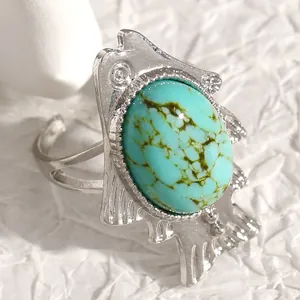 Macro detail of a vintage ethnic fish-shaped ring with an oval turquoise stone inlay.