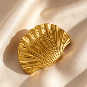 Detailed close-up view of a vintage gold scallop shell brooch on elegant satin fabric