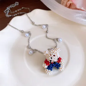 Close-up of beaded hollow bear pendant necklace with elegant white pearls on a plate.