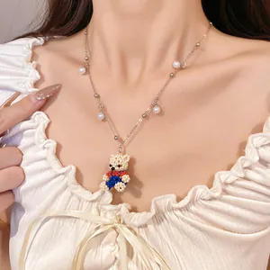 Close-up detail of a sweet beaded bear necklace featuring small white pearls on a model