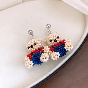 Detailed macro view of handcrafted colorful beaded bear earrings on a soft cream tray.