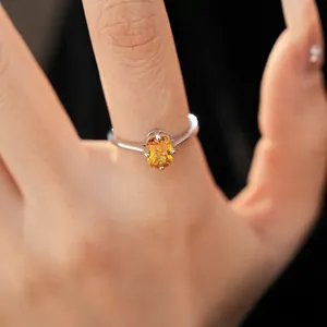 Bague minimaliste argentée avec zircon orange ovale portée sur le doigt d'une femme