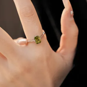 Gros plan d'une bague en argent ornée d'une pierre ovale vert olive sur une main