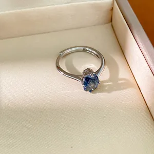 Gros plan d'une bague ajustable argentée avec pierre précieuse ovale bleue.
