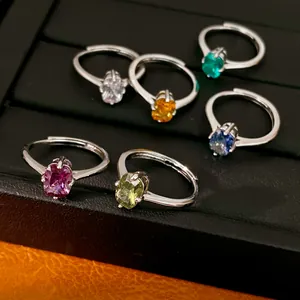 Détail de bagues en argent avec des zircons ovales colorés sur un plateau noir
