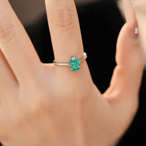 Détail macro d'une bague minimaliste en argent avec une pierre ovale verte sur la main