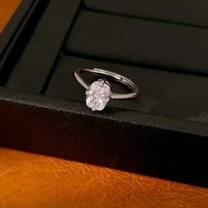 Zoom sur une bague ovale minimaliste en zircon avec anneau réglable argenté sur boîte.