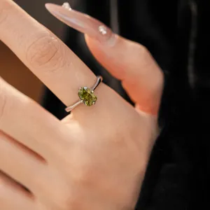 Gros plan d'une bague argentée avec une pierre de zircon ovale de couleur vert olive