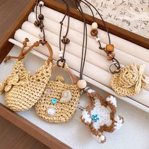 Detail von handgewebten Strohhut- und Taschenanhängern mit Holzperlen an Lederkordeln