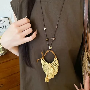 Nahaufnahme einer Boho-Halskette mit Strohanhänger, Holzperlen und braunem Lederband