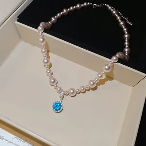 Primo piano di una collana di perle con ciondolo in zircone blu brillante in una scatola.