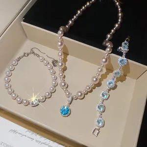 Elegante set di collana e bracciale di perle con pendenti in zircone blu scintillante.