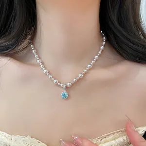 Elegante collana di perle con pendente tondo in zircone blu indossata
