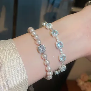 Dettaglio del set di bracciali con perle e zirconi blu scintillanti indossati al polso