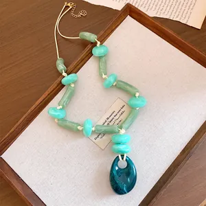 Bohemian style acrylic necklace featuring an oval pendant and mixed green beads.