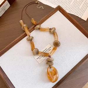 Detail view of a bohemian acrylic necklace with amber marble-patterned beads